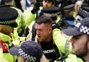 Tommy Robinson is led away by police officers as people take part in a march organised by the volunteer-led charity Campaign Against Antisemitism