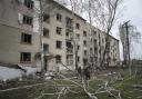 Local men cut a tree in front of a residential building which was heavily damaged by a Russian airstrike in Lukiantsi in the Kharkiv region