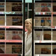 A woman looks at properties for sale in an estate agents - Photograph By Colin Mearns.