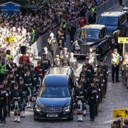 People gather in tribute as the cortege carrying the coffin of the late Queen Elizabeth II travels along the Royal Mile