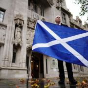 A Scottish independence supporter holds a Saltire outside the Supreme Court in London after the indyref2 ruling