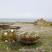 A general view of an abandoned building and old boat on the shoreline at North Ronaldsay, Orkney