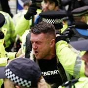 Tommy Robinson is led away by police officers as people take part in a march organised by the volunteer-led charity Campaign Against Antisemitism