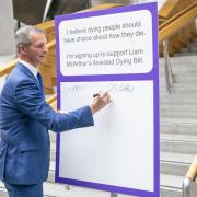 Liam McArthur signs a pledge card in support of his Assisted Dying Bill, at the Scottish Parliament