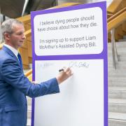 LibDem MSP Liam McArthur signing a pledge card in support of his Assisted Dying Bill