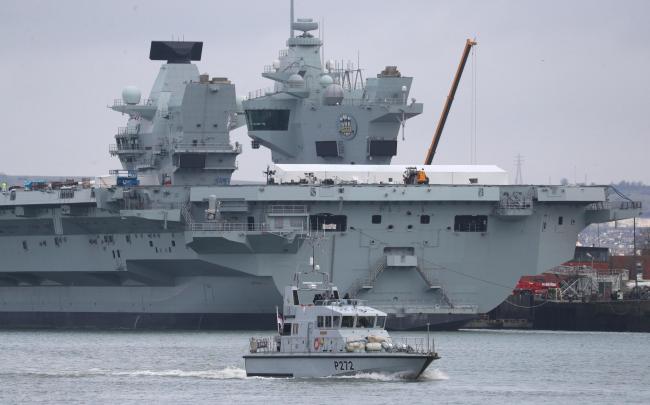 The Royal Navy archer class patrol vessel HMS Smiter passes the imaginatively named aircraft carrier HMS Prince of Wales