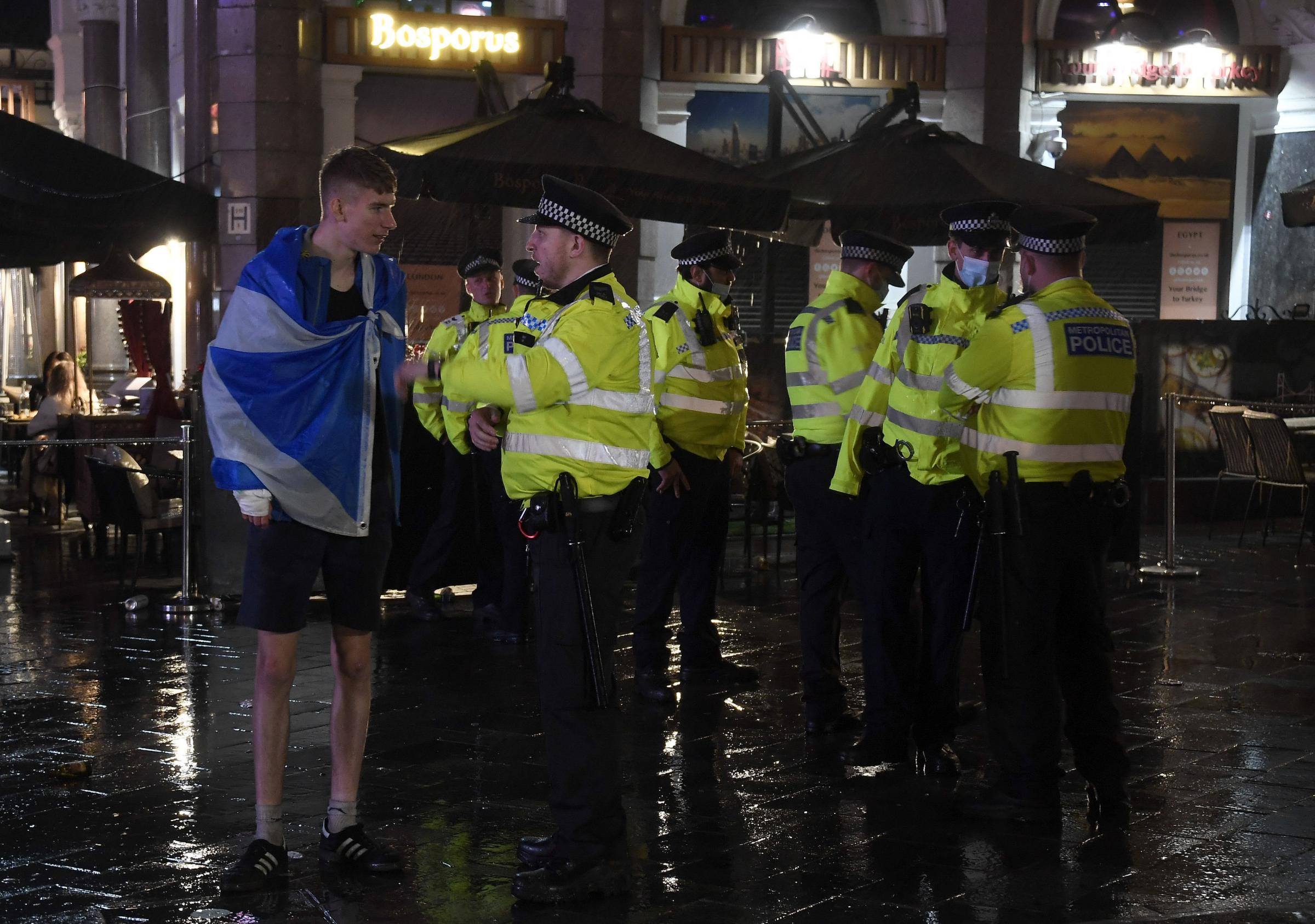 A Scotland supporter speaks to a police officer in Leicester Square in London, Friday, June 18, 2021 after the Euro 2020 soccer championship group D match between England and Scotland at Wembley Stadium. The match ended in a 0-0 draw.(AP Photo/Alberto