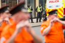 Police watch members of the County Grand Orange Lodge take part in the annual Orange walk parade through the city centre of Glasgow