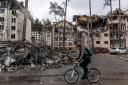 A man rides his bike past destroyed buildings in Irpin, Ukraine.