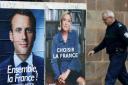 A man walks past posters promoting the French presidential election frontrunners Emmanuel Macron and Marine Le Pen