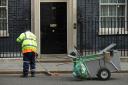 A street cleaner sweeps the road outside 10 Downing Street