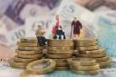 Models of elderly people on a pile of coins and banknotes