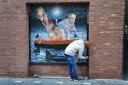 A mural by artist Ciaran Gallagher depicting Rishi Sunak aboard a dinghy named R.M.S Titanic, clinging on for dear life in shark-infested waters, whilst Boris Johnson and Penny Mordaunt prepare to jump overboard, which has been unveiled in Belfast after