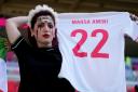 An Iran fan holding a shirt in memory of Mahsa Amini
