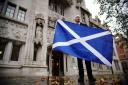 A Scottish independence supporter holds a Saltire outside the Supreme Court in London after the indyref2 ruling