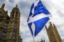 A member of public flies a giant Scottish Saltire flag outside the Houses of Parliament shortly before Scotland First Minister Nicola Sturgeon posed with newly-elected Scottish National Party (SNP) MPs during a photocall in London on May 11, 2015. The