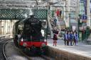 Piper Kevin MacDonald from the Red Hot Chilli Pipers with schoolchildren from the Royal Scottish Country Dance Society, during an event at Edinburgh Waverley station to mark the day the world famous locomotive, Flying Scotsman, entered service on