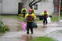 Members of the emergency services help local residents carry their possessions from homes in Brechin, Scotland