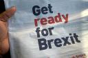 A person holds a newspaper with a UK Government advert urging people to 'get ready for Brexit'