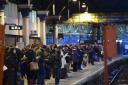 Commuters on a platform at Glasgow Queen Street Station wait for their trains