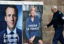 A man walks past posters promoting the French presidential election frontrunners Emmanuel Macron and Marine Le Pen