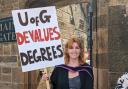 Glasgow University student Jess Wilson protests in her gown before graduating with a 'qualified' degree