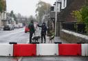 Dog walkers near a flood defence barrier erected on Church Street in the village of Edzell, Angus
