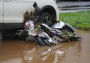 A moped covered in debris lies against a vehicle after being knocked over by flood water in Brechin