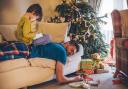 Father asleep on a sofa after a long and tiring Christmas Day, while his son sits on his back playing games on a digital tablet. Picture: Getty Images