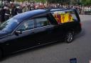 The coffin of Queen Elizabeth, draped with the Royal Standard of Scotland, passing the war memorial in Ballater on September 11, 2022