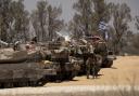 Israeli soldiers stand near tanks a long the border with the Gaza Strip on May 29, 2024