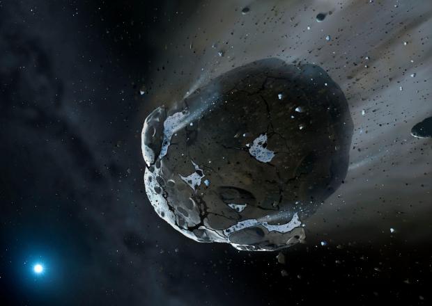 The National: Handout artist's impression issued by the University of Warwick of a water-rich asteroid being torn apart by the strong gravity of the white dwarf star. Similar objects probably delivered most of the water on Earth, scientists believe. PRESS