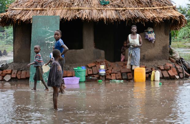The National: In this photo taken Thursday, Jan, 15, 2015, a family that survived flood waters wait outside they home for relief teams in the southern district of Chikwawa, near Blantyre, Malawi.  At least 176 people are confirmed dead and at least 200,000 have been