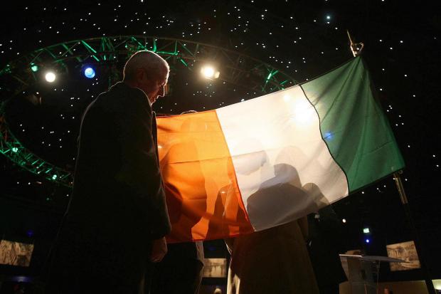 The National: A Sinn Fein worker adjusts the Irish flag on stage at the Mansion House Dublin