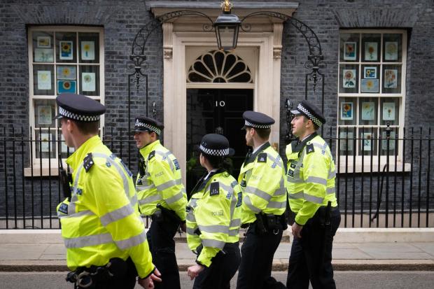 The National: A group of police officers walk through Downing Street, in Westminster, London, during a protest outside the gates. PA Photo. Picture date: Wednesday April 13, 2022. Prime Minister Boris Johnson and Chancellor Rishi Sunak have been fined as part of a