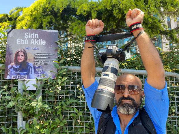 The National: Ibrahim Almasri, an Egyptian freelance photographer, wraps his camera straps around his wrists like handcuffs during a protest as dozens of pro-Palestinian demonstrators gathered near the Israeli Consulate in Istanbul, Turkey, to denounce the death of Abu Akleh (Mehmet Guzel/AP)