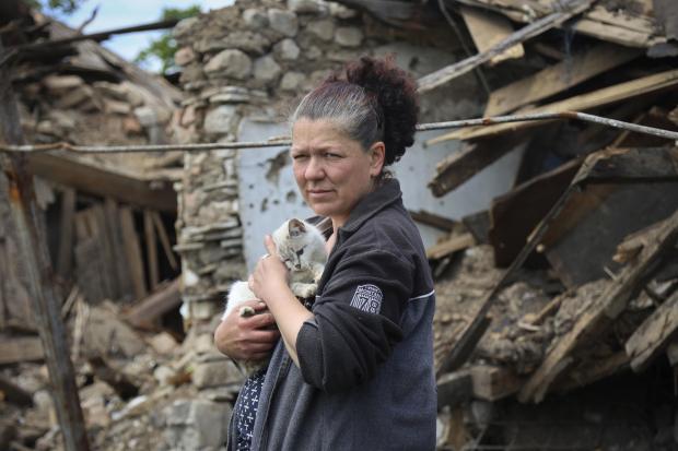 The National: A woman stands next to a destroyed house in Mariupol