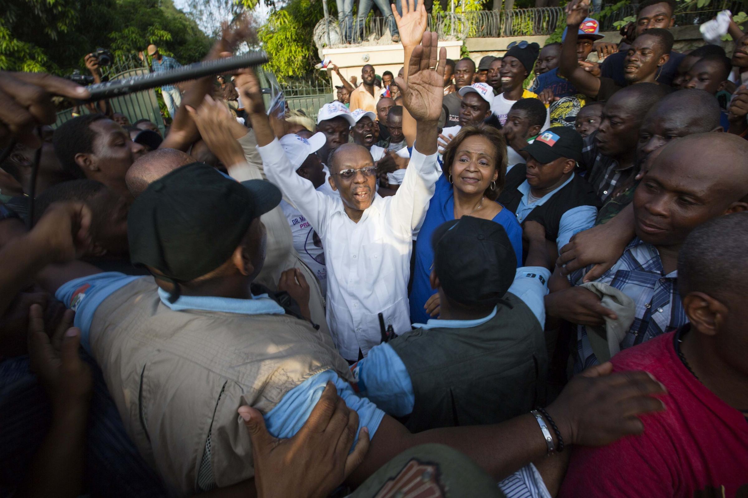 Haitis former President Jean Bertrand Aristide, center, waves to the crowd after he urged supporters to vote for presidential candidate Maryse Narcisse, center right, of the Fanmi Lavalas political party, in Port-au-Prince, Haiti, Wednesday Sept. 30,