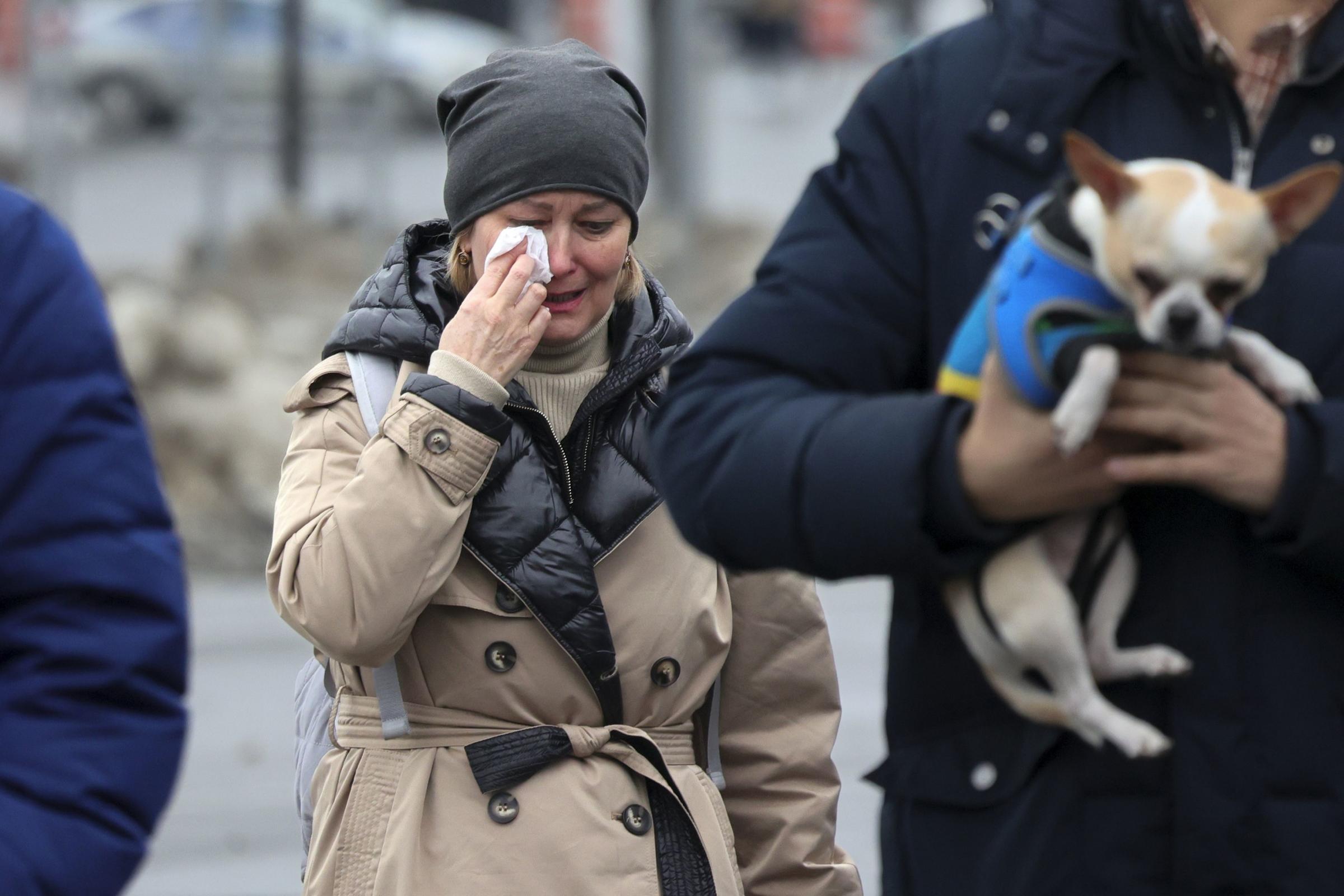 A woman reacts as she comes to place flowers at the fence next to the Crocus City Hall, on the western edge of Moscow, Russia, Saturday, March 23, 2024, following an attack Friday, for which the Islamic State group claimed responsibility. Russian