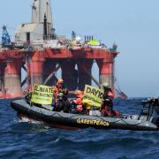 Greenpeace activists in an inflatable boat display banners at a BP rig protest in the North Sea