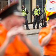 Police watch members of the County Grand Orange Lodge take part in the annual Orange walk parade through the city centre of Glasgow