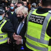 Prime Minister Boris Johnson is surrounded by police as he arrives at Glasgow Central station for a second visit to COP26
