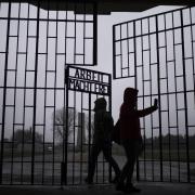 Persons take photos as they enter the Sachsenhausen Nazi death camp through the gate with the phrase 'Arbeit macht frei' (work sets you free), in Oranienburg, about 30 kilometers (18 miles) north of Berlin, Germany