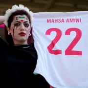 An Iran fan holding a shirt in memory of Mahsa Amini