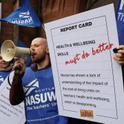 A member of the NASUWT teaching union holds a 'report card' for Nicola Sturgeon outside her Glasgow office