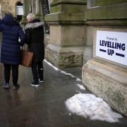Shoppers walk past a 'Powered By Levelling Up' sign put up by Rishi Sunak and his Chancellor, Jeremy Hunt