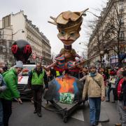 Protesters pull an effigy of President Macron during a march against pension reforms