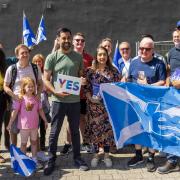 First Minister of Scotland Humza Yousaf holds a Yes sign with SNP activists during campaigning in Pollok, Glasgow