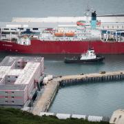 A tug boat passes the Bibby Stockholm accommodation barge at Portland Port in Dorset, which will house up to 500 people.