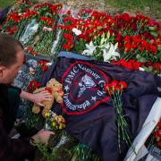 A man lays flowers in memory of Yevgeny Prigozhin at a spontaneous memorial near the PMC Wagner Center